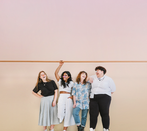 four women posing and smiling while wearing Noz facial sunscreen on their nose 