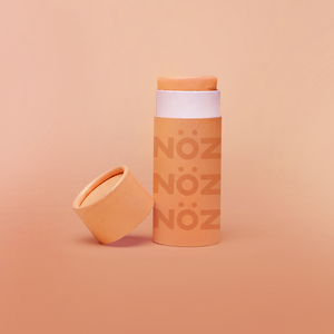 Noz Sunscreen in orange, with the cap off showing the stick of colorful sunscreen inside