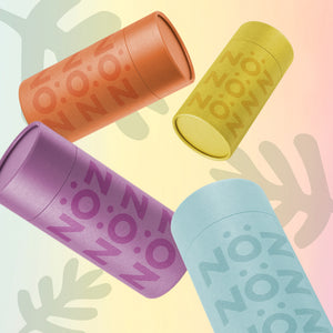 Noz sunscreen in its four colors: orange, yellow, purple and blue are scattered on a soft colorful background. 